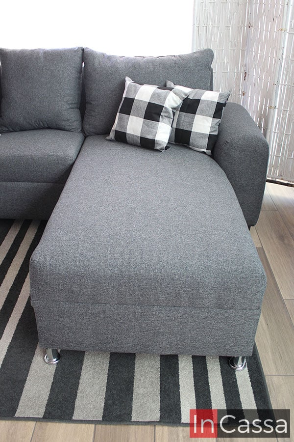 La foto se concentra en el chaise long de la sala, el cuál es bastante largo y con buena amplitud para ofrecer un asiento cómodo y reconfortante. La cercanía de la toma ofrece una mejor vista del tapiz lino mouse presente en toda la sala.