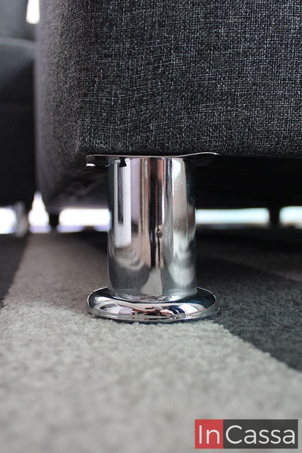 Foto de una de las patas que sostienen la sala, las cuales son metálicas con un acabado cromado. Además, la toma también permite apreciar de manera más cercana la textura del tapiz lino mouse de la sala.