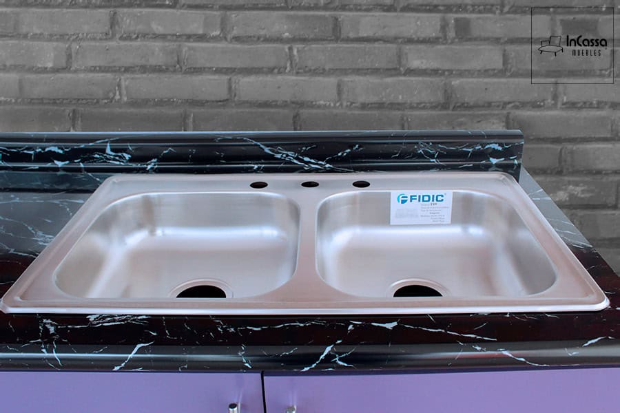 La fotografía destaca la tarja doble de acero inoxidable de la Cocina Integral OKAYAMA de 3.60m para ESTUFA en color morado, integrada sobre cubierta de formaica en estilo mármol negro que aporta amplitud, funcionalidad y un elegante contraste moderno.