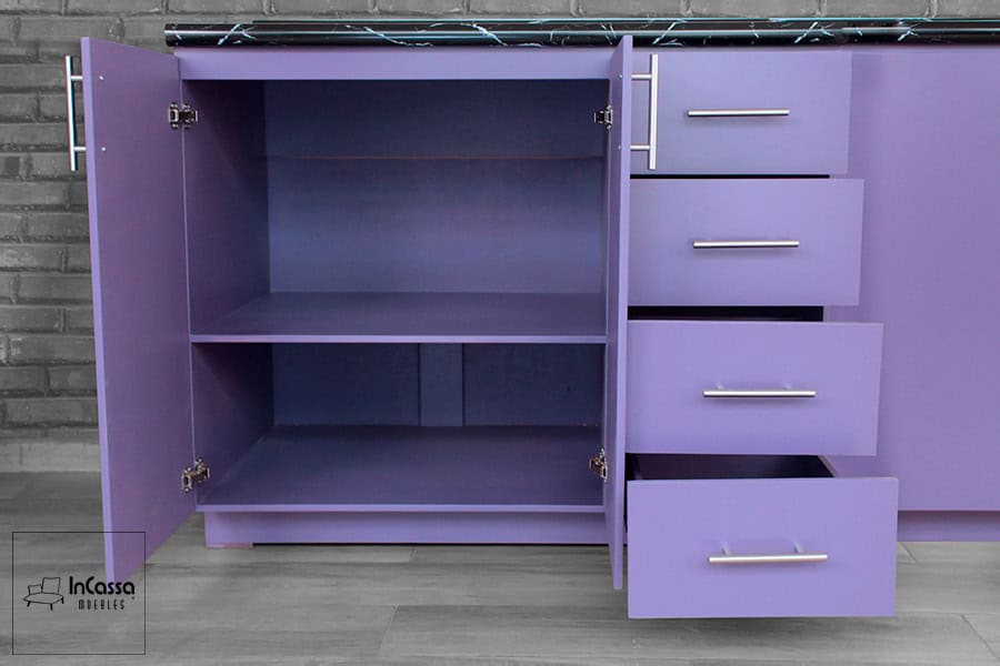 Se observa el módulo inferior de la Cocina Integral OKAYAMA para parrilla, terminado en elegante color uva. Incluye cuatro cajones amplios con correderas metálicas y un compartimento doble con estante interior, ideal para organizar utensilios y ollas sobre cubierta estilo mármol negro.