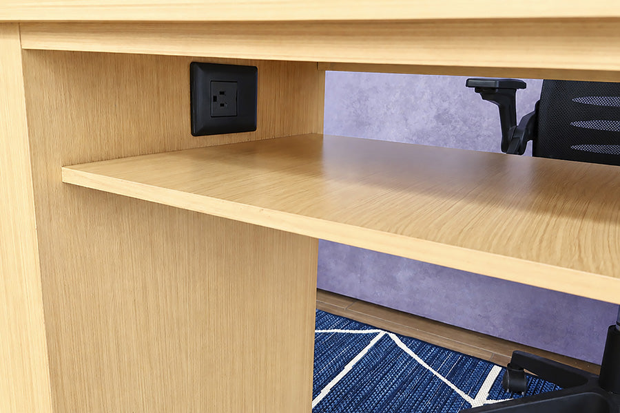 Un acercamiento al Escritorio estilo Lambrín Modelo ORLEANS en color natural muestra el compartimento abierto bajo la cubierta, con una repisa amplia para organizar accesorios. En el panel posterior se integra un contacto eléctrico, facilitando la conexión de equipos directamente desde el área de trabajo.