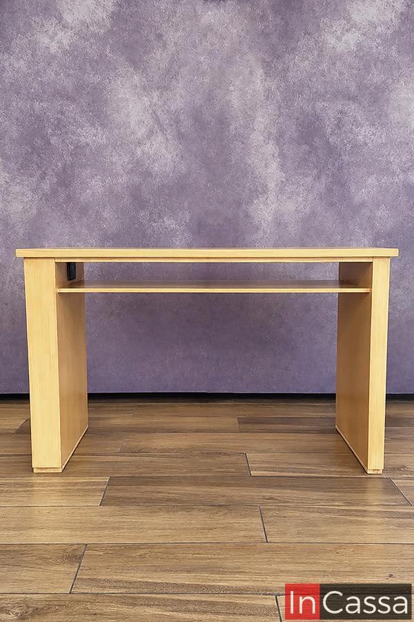 Vista posterior del Escritorio estilo Lambrín Modelo ORLEANS en color natural, donde se aprecia su estructura limpia y funcional. Cuenta con una repisa amplia bajo la cubierta para organizar accesorios o equipo de trabajo, además de un contacto eléctrico integrado que facilita la conexión de dispositivos.