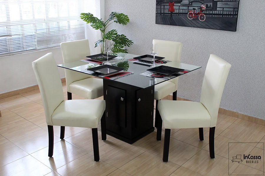 La foto muestra el Comedor Modelo OSLO para 4 personas, con mesa de cristal y pedestal en color chocolate. Las sillas tapizadas en tacto piel tono hueso complementan su diseño moderno y elegante ideal para espacios contemporáneos.
