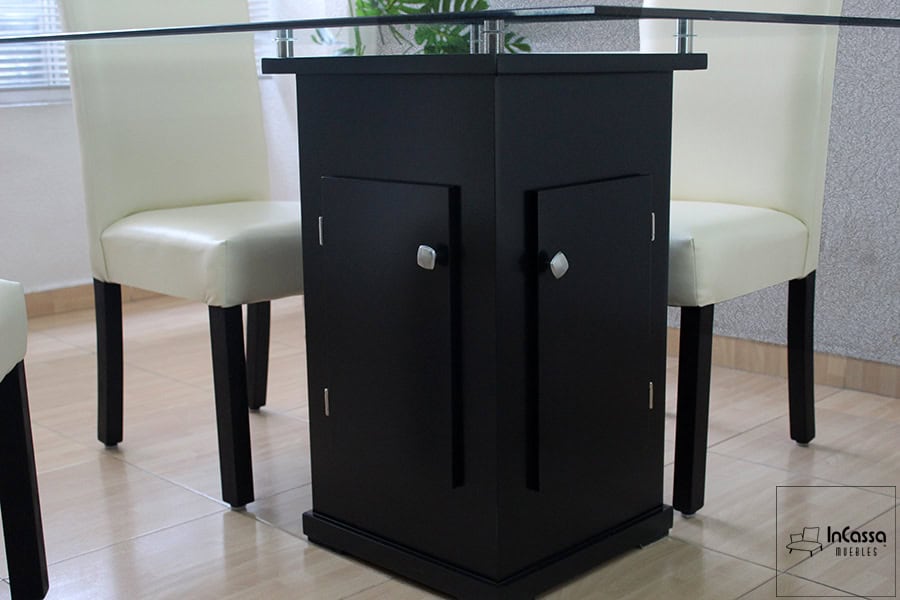 La imagen destaca el pedestal central del Comedor Modelo OSLO, fabricado en color chocolate con puertas funcionales para almacenamiento. Su base sostiene una cubierta de cristal templado, aportando elegancia y practicidad al diseño.