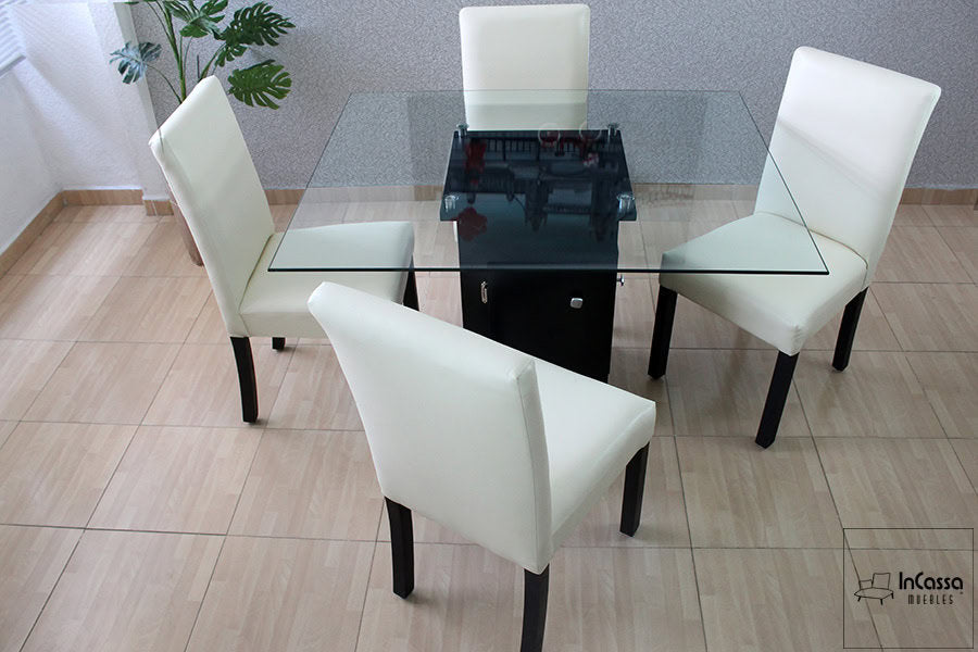 La fotografía presenta el Comedor Modelo OSLO visto desde arriba, con mesa de cristal templado y base central en color chocolate. Las cuatro sillas en tacto piel tono hueso completan su estilo elegante y contemporáneo.