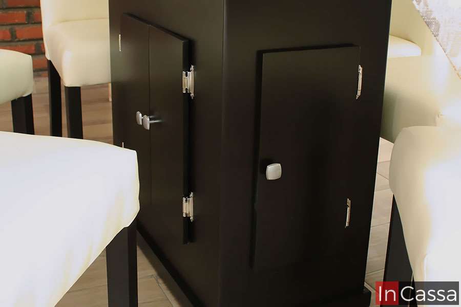 La imagen muestra un acercamiento al pedestal del Comedor Modelo OSLO para 6 personas, elaborado en color chocolate con puertas funcionales y herrajes metálicos. Su diseño robusto aporta estabilidad y estilo al conjunto.