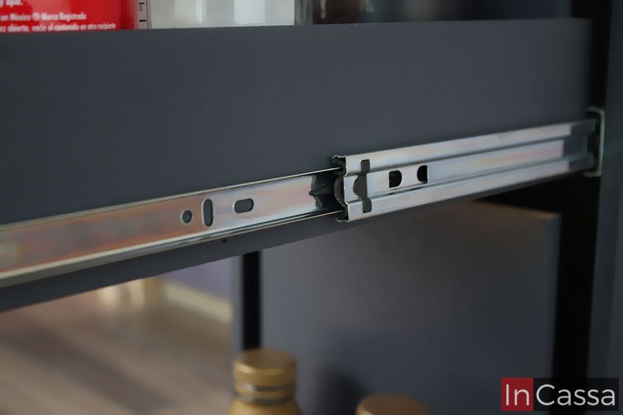 La imagen muestra el sistema de correderas metálicas de extensión que permite un deslizamiento suave y seguro del cajón del despensero gris oxford. Este mecanismo garantiza durabilidad y practicidad en el uso diario.