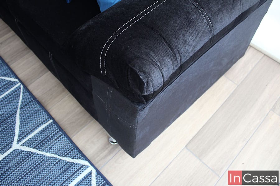 Está toma resalta el acabado acolchonado de los descansa brazos tapizados en suede negro, además también es posible apreciar parte de la base del love seat tapizado en la misma tela y color.
