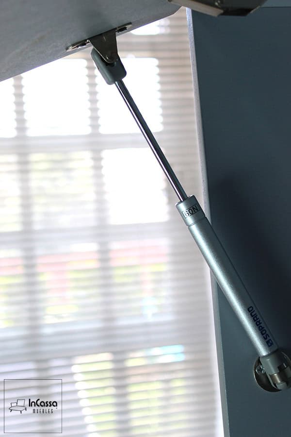 Una toma cercana al pistón neumático que asegura la apertura suave de la puerta del mueble sobre campana, proporcionando comodidad y seguridad al abrir el gabinete.