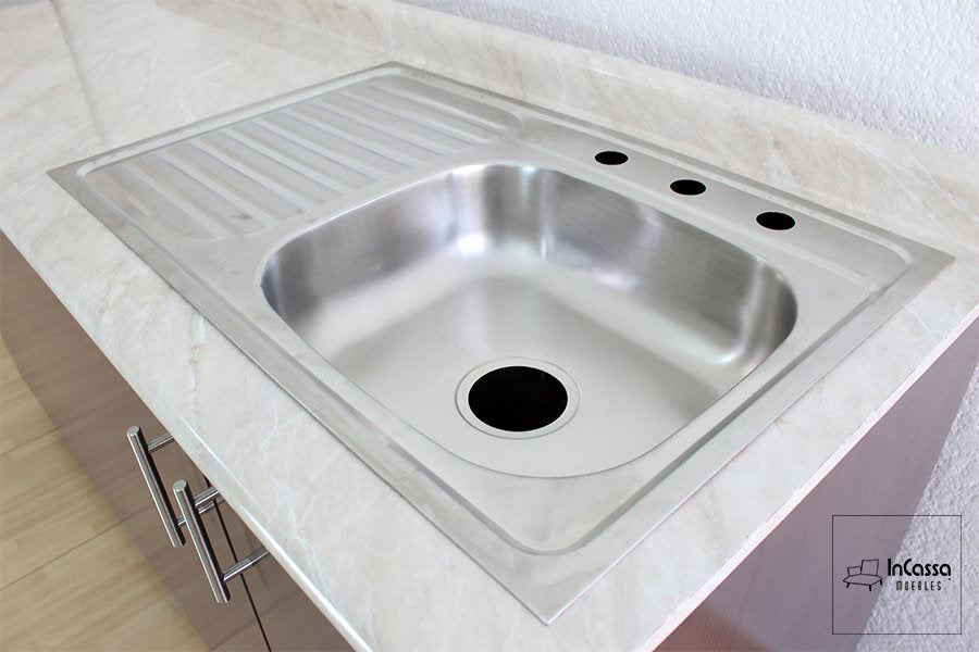 Una toma cercana resalta la tarja de acero inoxidable con escurridor incluida en la cocina Palmeira, montada sobre una cubierta de formaica en estilo blanco fresh que aporta elegancia y resistencia al uso diario.