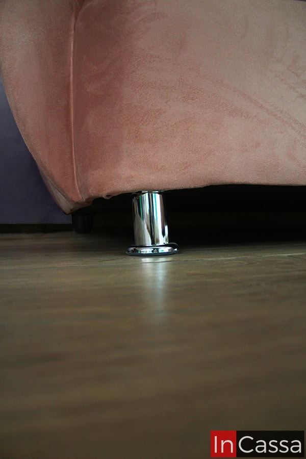 La toma en primer plano destaca la pata metálica cromada del modelo PAMPLONA, contrastando con el tapizado en suede rosa palo. Su acabado brillante aporta estabilidad, estilo moderno y un toque de sofisticación al diseño general del mueble.