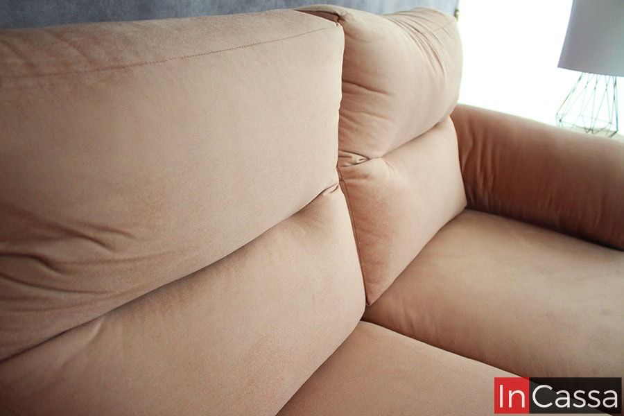 La imagen resalta el tapizado suave en suede rosa palo del respaldo y asiento del modelo PAMPLONA. Su acolchado generoso y costuras finas ofrecen un confort envolvente, ideal para crear un ambiente cálido, elegante y lleno de estilo contemporáneo.