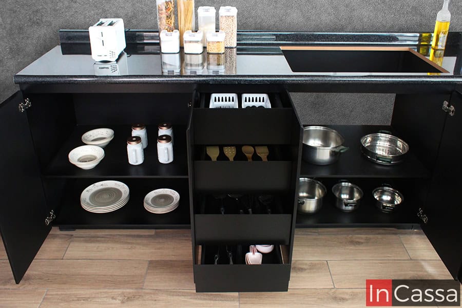 La cocina incluye módulos inferiores en color chocolate completo con cajones y compartimentos amplios, ideales para almacenar desde cubiertos hasta platos y tazas, manteniendo todo al alcance de la mano.