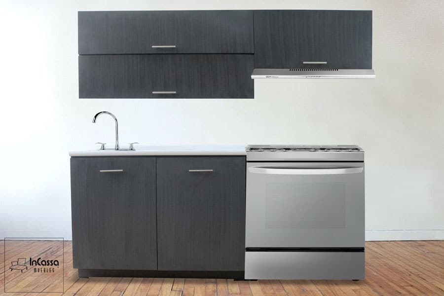 Una toma frontal de la Cocina Integral Modelo PISA para Estufa en tono gris cenizo oscuro. Incluye módulos superiores y una campana integrada, así como módulos inferiores con cubierta de formaica en estilo sal y pimienta. El diseño simétrico luce moderno y elegante sobre muro de ladrillo expuesto.