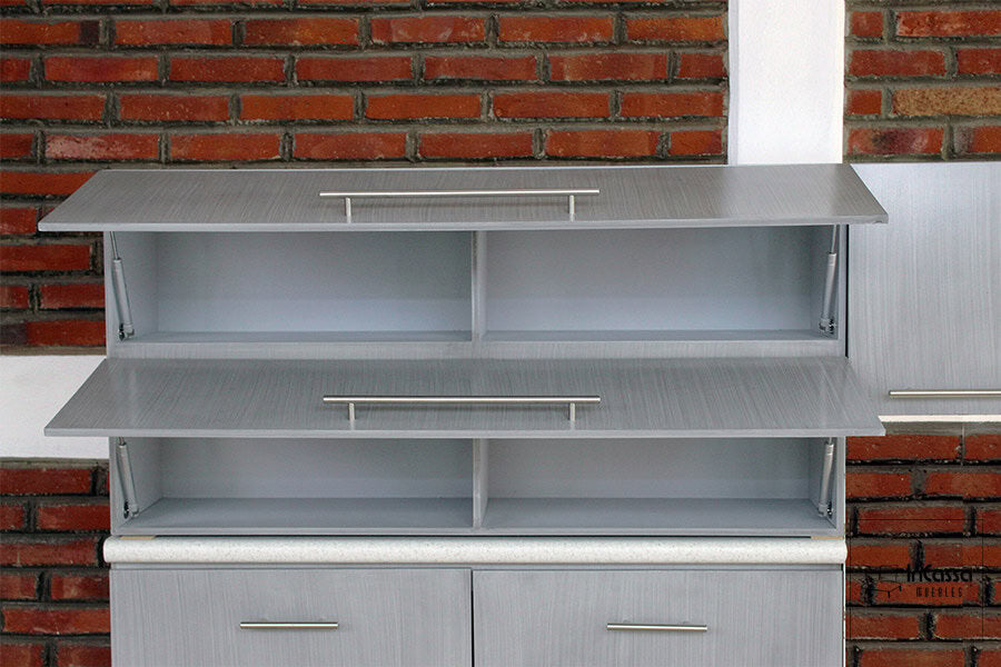 La imagen presenta una toma frontal de las alacenas superiores del modelo PISA para Estufa, con puertas abatibles abiertas hacia arriba mediante pistones neumáticos. Se aprecian 4 compartimentos amplios, ideales para organizar vajillas, despensa o utensilios de cocina. El diseño moderno en tono gris cenizo claro y jaladeras metálicas resalta sobre el fondo de ladrillo.