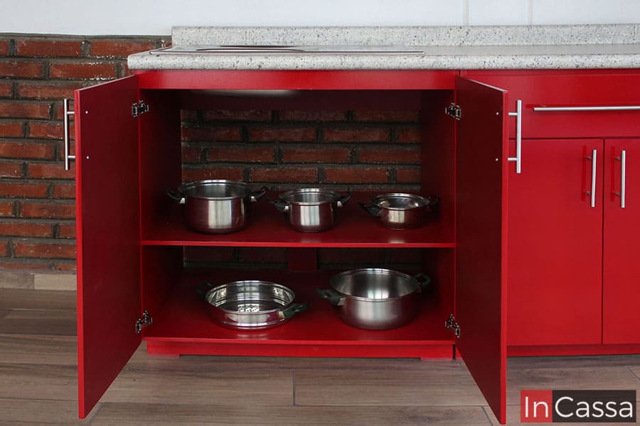 La toma se enfoca en los interiores del lado izquierdo del módulo inferior, cuyo espacio está divido por un entrepaño en dos compartimentos horizontales, además la parte trasera de la estructura queda libre dejando ver la pared, esto con el fin de hacer posible la instalación de plomería para la tarja. Los interiores así como los exteriores del módulo son de color rojo en su totalidad.