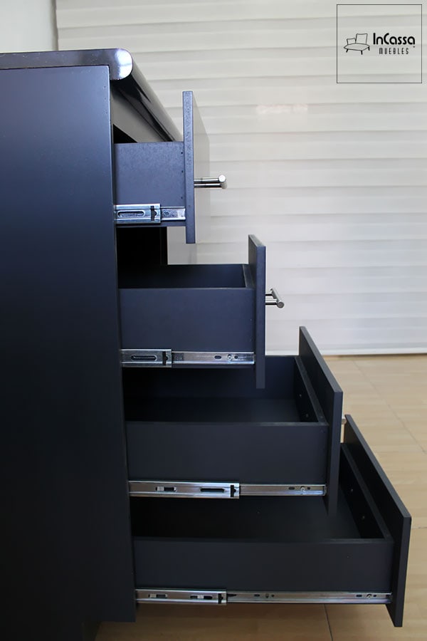 La toma lateral muestra el módulo inferior de la Cocina Integral QUEBEC para Estufa, con cuatro amplios cajones funcionales con correderas metálicas de extensión total, que permiten una apertura suave y acceso completo al interior. Cada cajón está equipado con jaladeras de acero inoxidable que aportan elegancia y modernidad al diseño. El acabado en MDF Chileno color gris oxford y la cubierta de formaica tipo mármol negro completan un estilo sofisticado, ideal para cocinas contemporáneas y prácticas.