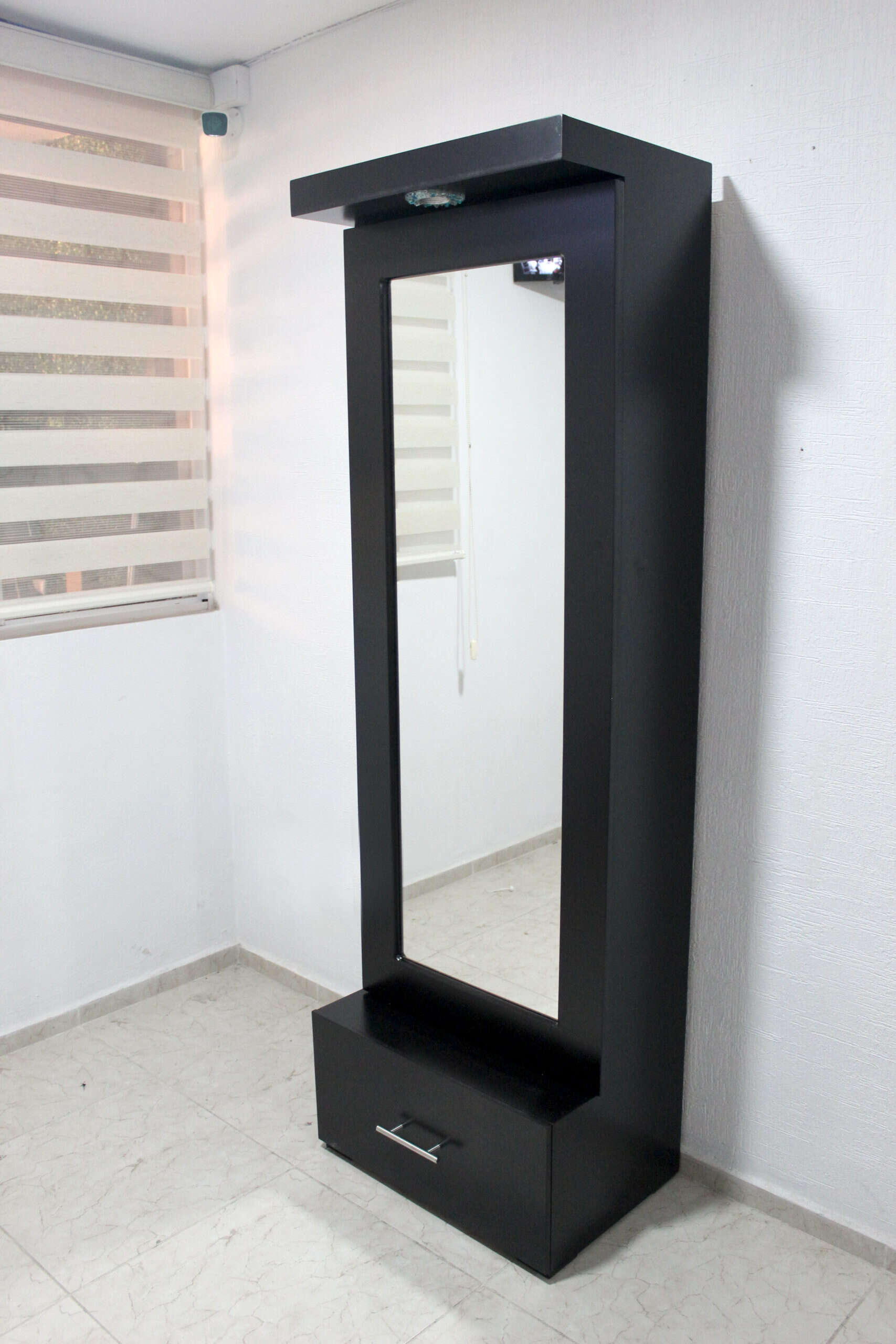 Una toma en ángulo derecho muestra el espejo vestidor Queens con acabado chocolate mate. Su diseño estilizado integra luz en la parte superior, espejo de cuerpo completo y cajón inferior con jaladera metálica, ideal para espacios pequeños y modernos.