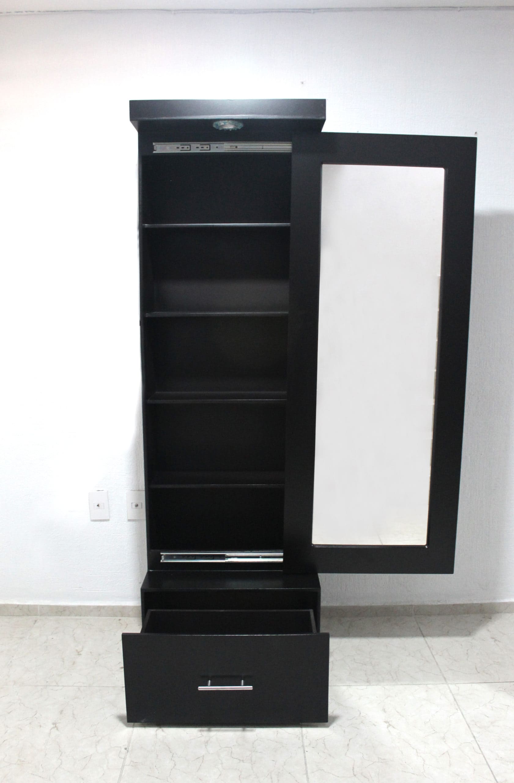 Una vista frontal revela el interior del espejo vestidor modelo Queens, con puerta abierta que oculta repisas internas en acabado chocolate. Incluye luz superior, estantes amplios y un cajón inferior, ideal para guardar maquillaje, accesorios o perfumes con estilo y orden.