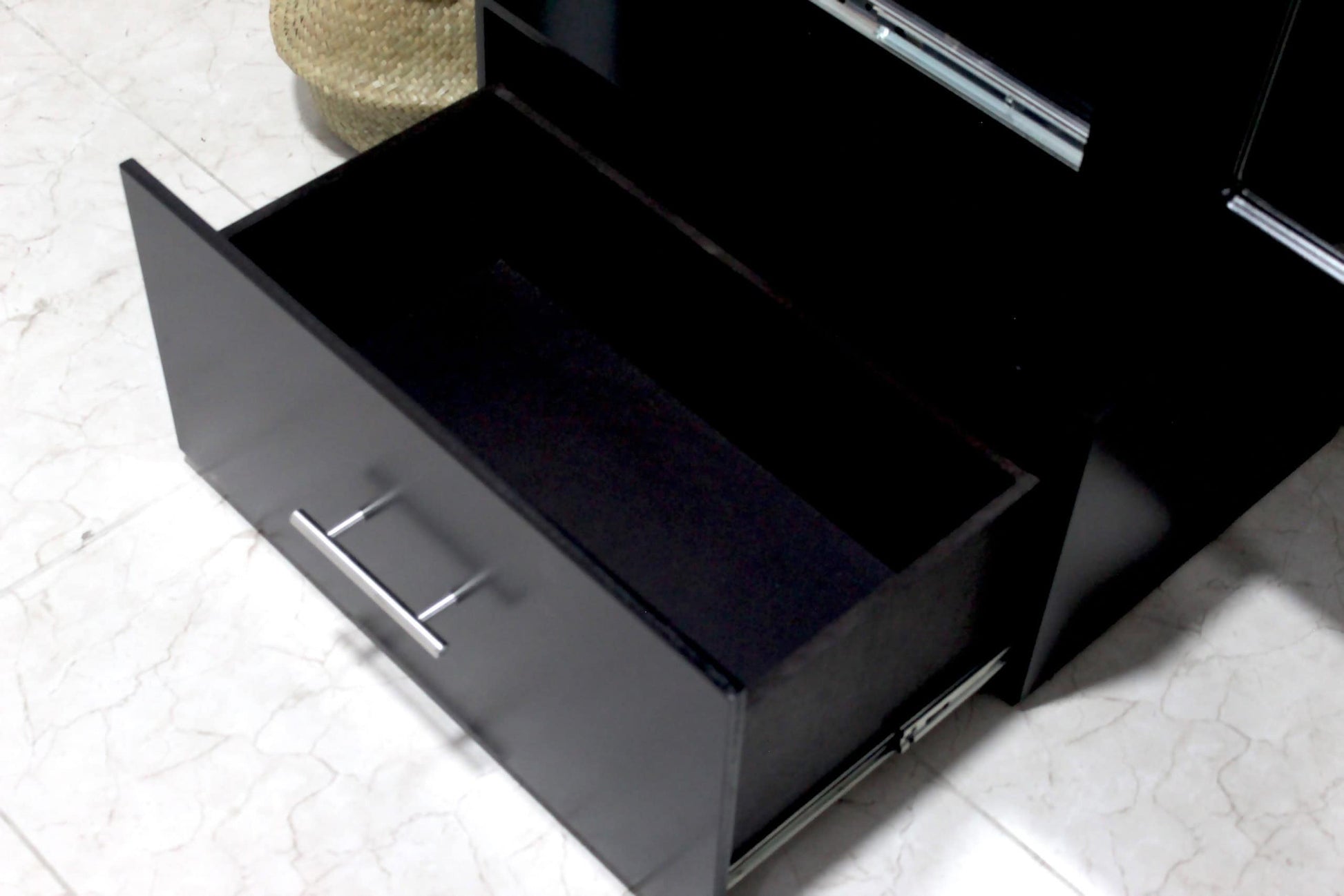 Una toma cercana destaca el cajón inferior del espejo vestidor Queens en acabado chocolate, abierto y con rieles metálicos de extensión. Su interior espacioso permite guardar artículos personales, mientras que la jaladera cromada añade un toque moderno y funcional.