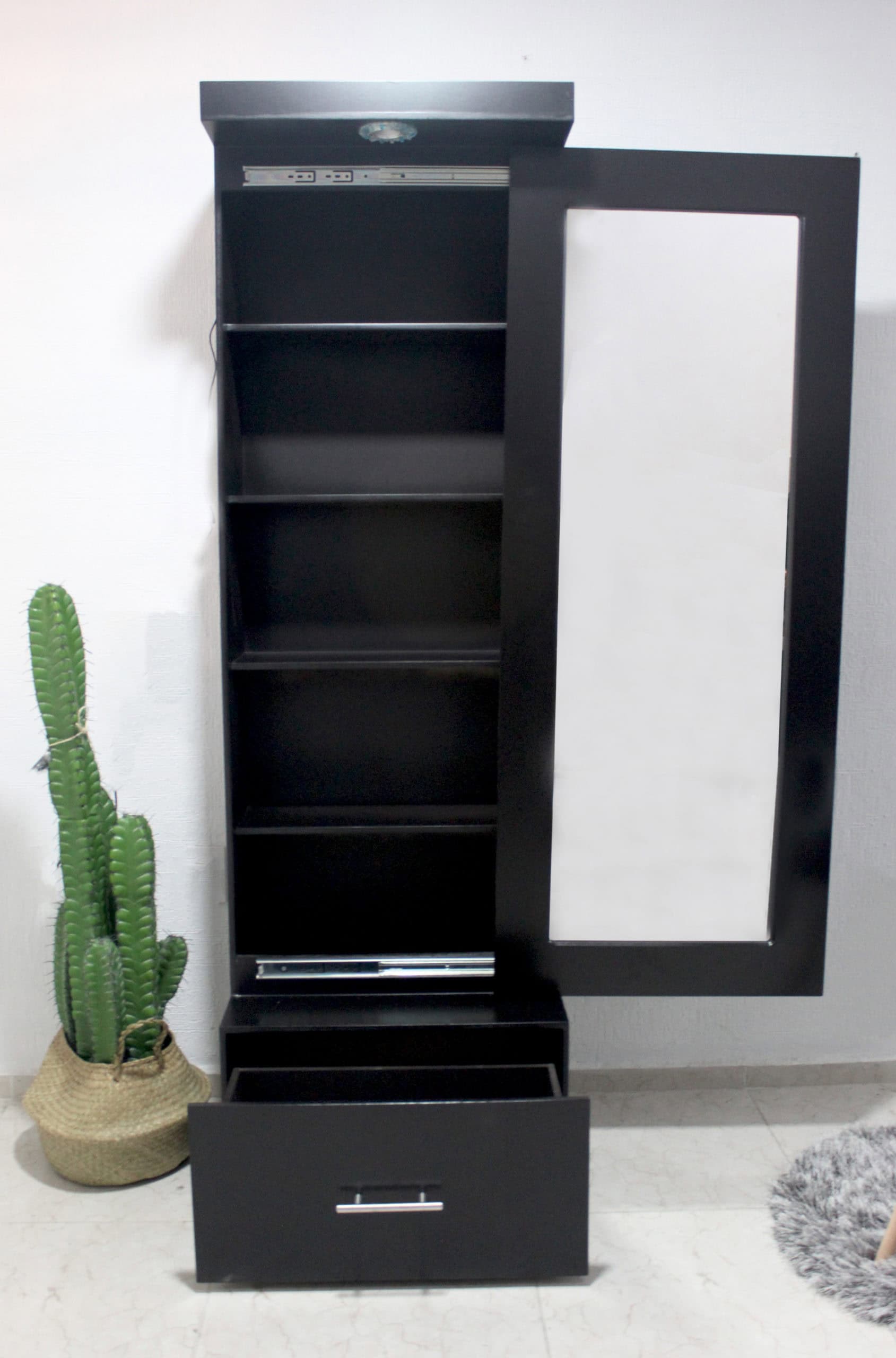 La imagen muestra el espejo vestidor Queens con la puerta abierta, revelando cinco repisas internas y un cajón inferior amplio. El diseño moderno en chocolate mate incluye luz integrada y riel telescópico, ideal para mantener todo organizado y oculto con estilo.