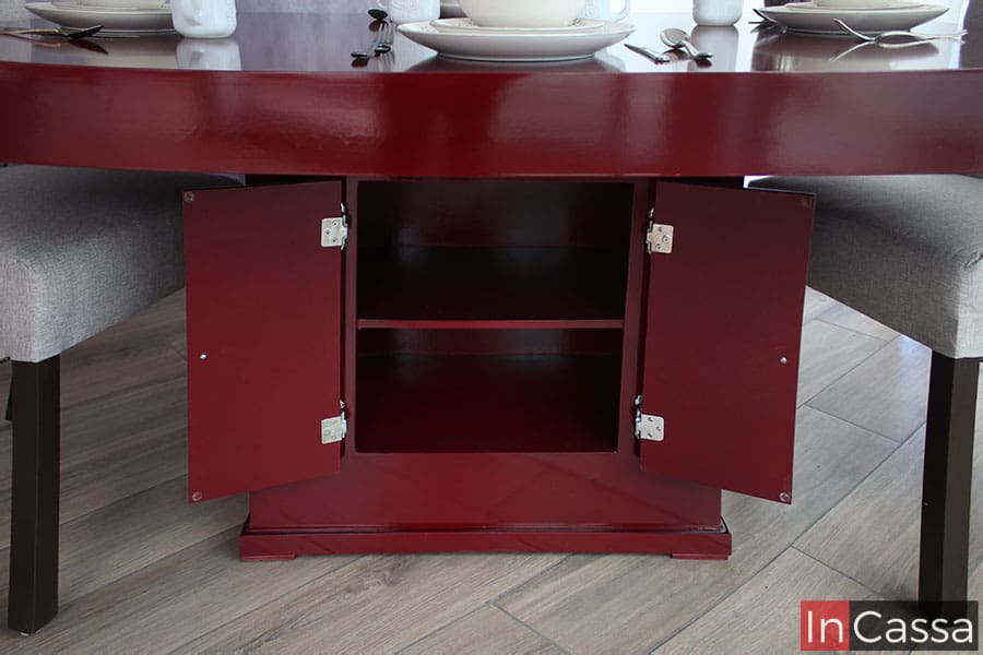 Esta imagen nos permite observar el interior del compartimento del pedestal, mostrando el entrepaño con el que cuenta así como su color borgoña, mismo que se conserva en la totalidad del mueble. También es posible ver el sistema de bisagras en ambas puertas incorporadas en el pedestal.