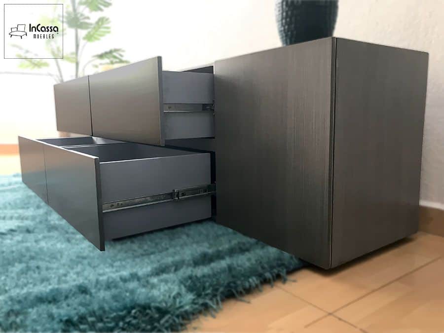 La fotografía muestra los cajones abiertos del modelo QUITO, revelando sus correderas metálicas de extensión que garantizan un deslizamiento suave y duradero. El acabado en gris cenizo oscuro realza su diseño contemporáneo y sofisticado.