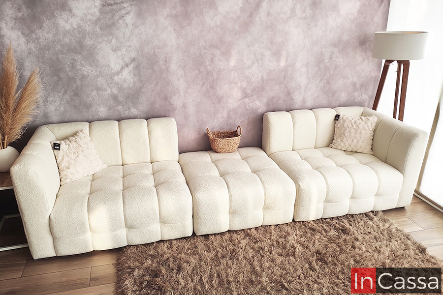 Se aprecia la Sala tipo NUBE Modular Modelo RODAS tapizada en suede hueso, configurada en módulos independientes que permiten adaptar su distribución según el espacio. Su diseño acolchado tipo nube, con líneas curvas y asientos amplios, ofrece gran comodidad y un estilo contemporáneo, mientras que el elegante tono hueso aporta luminosidad y calidez a cualquier sala.
