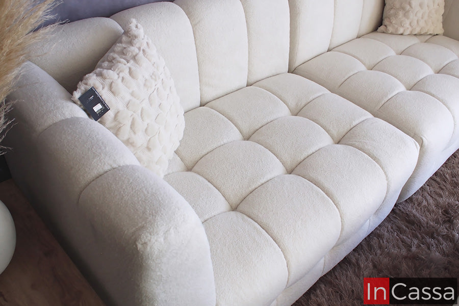 La imagen muestra un acercamiento a la Sala tipo NUBE Modular Modelo RODAS tapizada en suede hueso, resaltando el diseño de sus amplios asientos y respaldo con acolchado tipo nube. Su tapizado de textura suave, brazos curvos y acabado en tono hueso crean una apariencia elegante, acogedora y contemporánea, ofreciendo un excelente nivel de confort para disfrutar momentos de descanso.