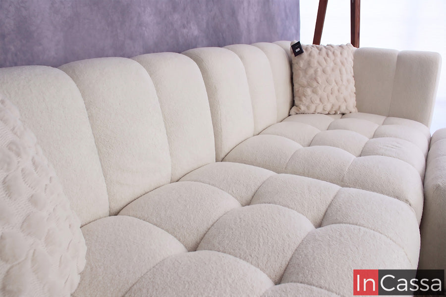 Se aprecia un acercamiento a la Sala tipo NUBE Modular Modelo RODAS tapizada en suede hueso, destacando el elegante diseño de su respaldo envolvente y el característico acolchado tipo nube en los asientos. Su tapizado de textura suave brinda una sensación acogedora, mientras que sus líneas curvas y acabado en tono hueso aportan sofisticación, confort y un estilo contemporáneo ideal para cualquier espacio.