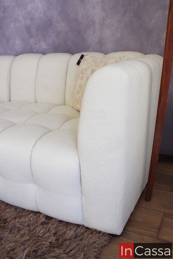 Se observa un detalle lateral de la Sala tipo NUBE Modular Modelo RODAS tapizada en suede hueso, resaltando el diseño redondeado de su brazo y la continuidad del acolchado tipo nube que caracteriza tanto el respaldo como el asiento. Su tapizado en tono hueso y textura suave crea una apariencia elegante y acogedora, convirtiéndola en una pieza ideal para quienes buscan comodidad, amplitud y un estilo contemporáneo en su sala.