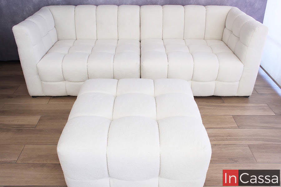 Se aprecia la Sala tipo NUBE Modular Modelo RODAS tapizada en suede hueso, acompañada de un amplio otomán independiente que complementa su diseño y funcionalidad. Su estilo de inspiración orgánica destaca por los módulos acolchados de formas redondeadas, respaldos envolventes y una textura suave que invita al descanso. El acabado en tono hueso aporta elegancia, luminosidad y un aire contemporáneo, convirtiendo este conjunto en la opción ideal para crear espacios acogedores y sofisticados.