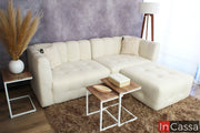 La imagen presenta una sala modular tipo nube Modelo RODAS en suede color hueso, capturada en vista frontal amplia; su diseño capitoneado y formas suaves aportan confort y elegancia, complementada con mesas laterales y tonos neutros que crean un ambiente moderno y acogedor.