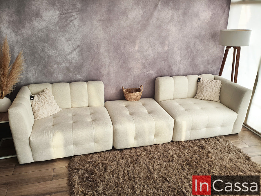 Una vista panorámica muestra la sala modular tipo nube Modelo RODAS en suede color hueso, compuesta por módulos independientes capitoneados; su diseño versátil permite múltiples configuraciones, creando un ambiente moderno, cómodo y perfectamente adaptable a cualquier espacio.