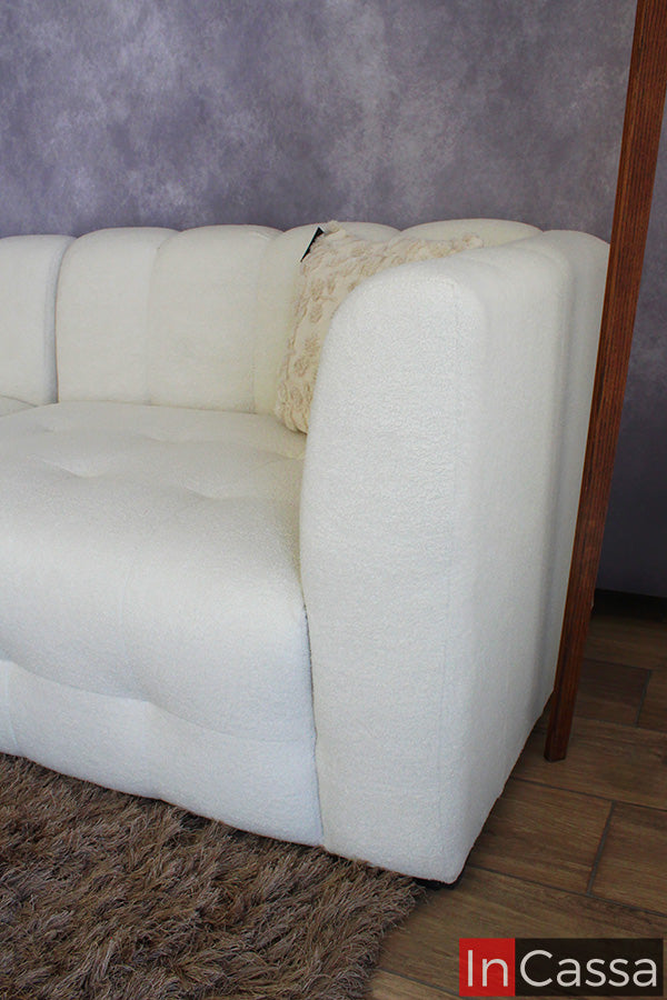 En esta toma lateral se destaca el brazo redondeado de la sala modular RODAS en suede color hueso, mostrando su acabado suave y voluminoso; su diseño curvo y acolchado brinda una sensación envolvente, ideal para espacios modernos y altamente confortables.