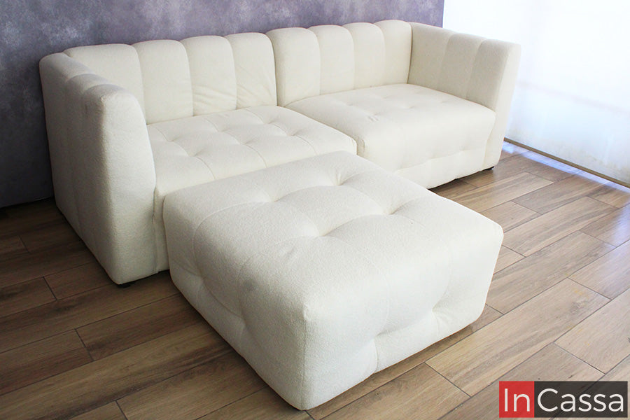 La imagen presenta la sala modular RODAS en suede color hueso desde un ángulo amplio, destacando su módulo tipo puff al frente; su capitoneado y líneas curvas crean un diseño moderno, cómodo y versátil, ideal para adaptarse a distintos espacios.