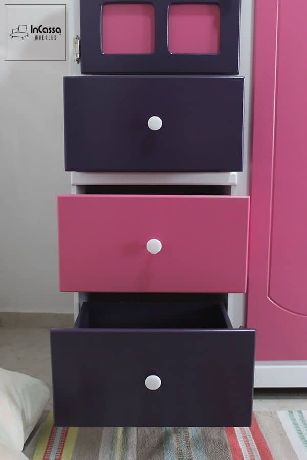 En esta imagen se aprecia la cajonera del Roperito Infantil Modelo ROMINA, con tres amplios cajones en tonos rosa pastel y uva. Cada cajón cuenta con tiradores redondos blancos que aportan un toque tierno y elegante, ideales para guardar ropa, juguetes o accesorios en la habitación de los más pequeños.