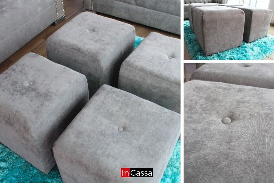 Una fotografía de cuatro taburetes tapizados en suede gris perla con textura suave y botones decorativos, dispuestos sobre una alfombra turquesa. Estos taburetes ofrecen versatilidad y estilo, perfectos para una sala moderna que busca funcionalidad y diseño.