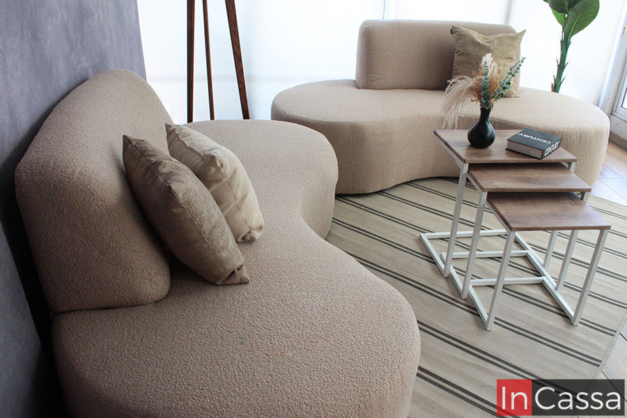 La toma lateral resalta los módulos curvos de la Sala Redonda Modelo SALÓNICA tapizada en suede gris perla. La textura suave y los cojines neutros aportan calidez, mientras las mesas laterales completan un ambiente moderno, elegante y armonioso.