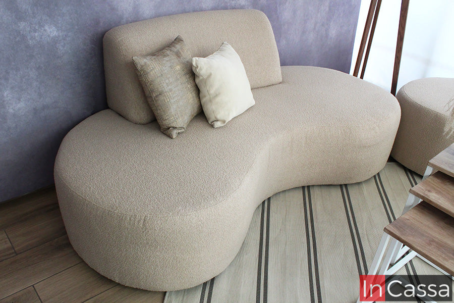 La imagen destaca un módulo de la Sala Redonda Modelo SALÓNICA, tapizado en suede gris perla, con formas suaves y envolventes. Sus líneas fluidas y cojines en tonos neutros crean un ambiente moderno, elegante y acogedor.