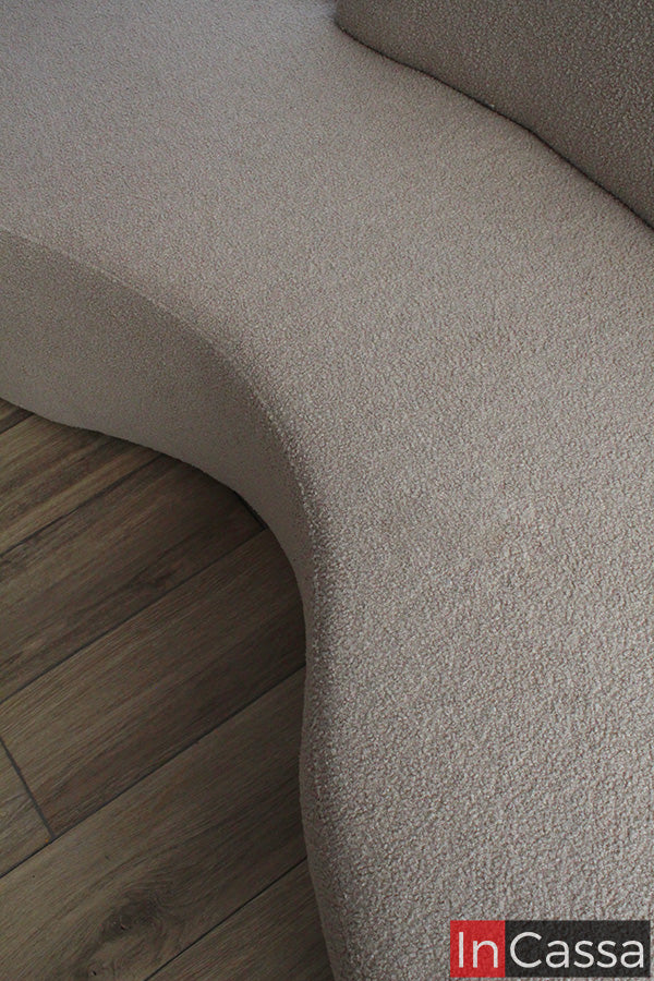 La toma cercana resalta la silueta fluida del módulo SALÓNICA, mostrando su base curva y tapizado en suede gris perla tipo bouclé. Su acabado uniforme y suave aporta elegancia, confort y un diseño moderno lleno de personalidad.