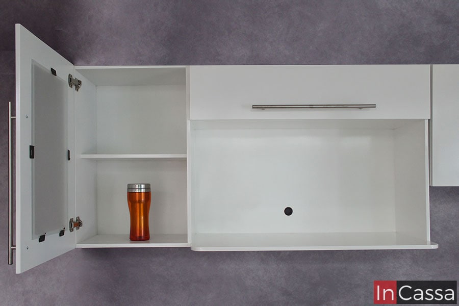 Podemos ver el modulo superior con espacio para microondas, cuya estructura es enteramente blanca tanto en su superficie así como en su interior. El compartimento lateral se muestra abierto, teniendo una vista del entrepaño que divide el espacio en dos partes.