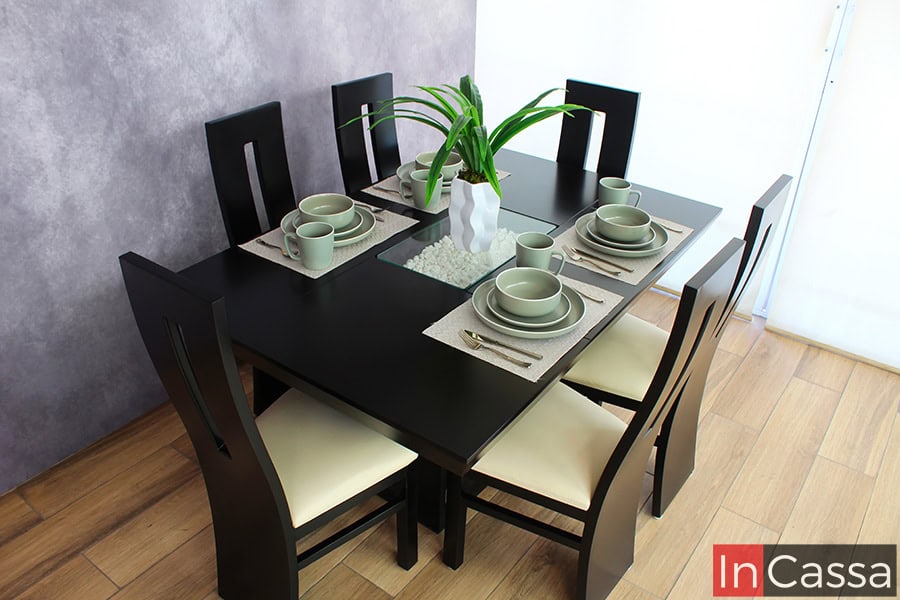 En esta imagen se aprecia el diseño simétrico del comedor para seis personas. Destaca la armonía entre el acabado chocolate de la estructura, el arenero central con piedras decorativas blancas y el contraste del tapizado suede hueso en las sillas.