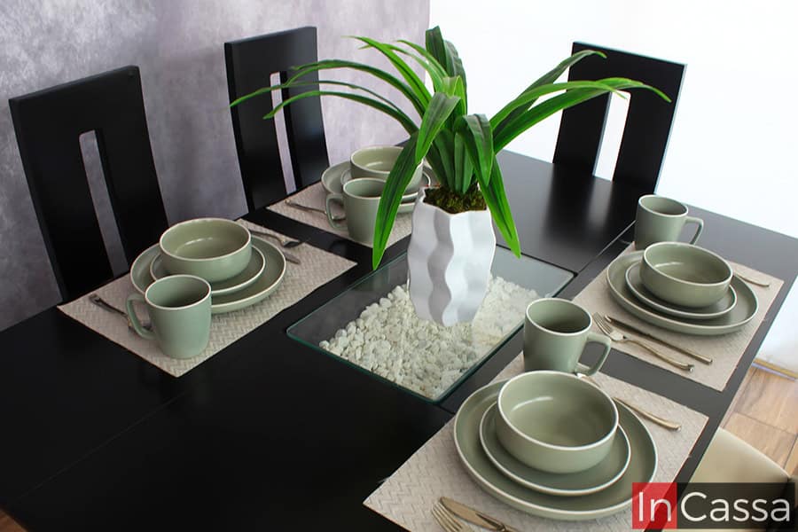 La imagen muestra el atractivo detalle central del comedor chocolate: un elegante arenero central que encierra piedras decorativas blancas, realzado con un florero blanco geométrico. Este toque distintivo enmarca con estilo la vajilla en tonos neutros y la armonía visual del conjunto.