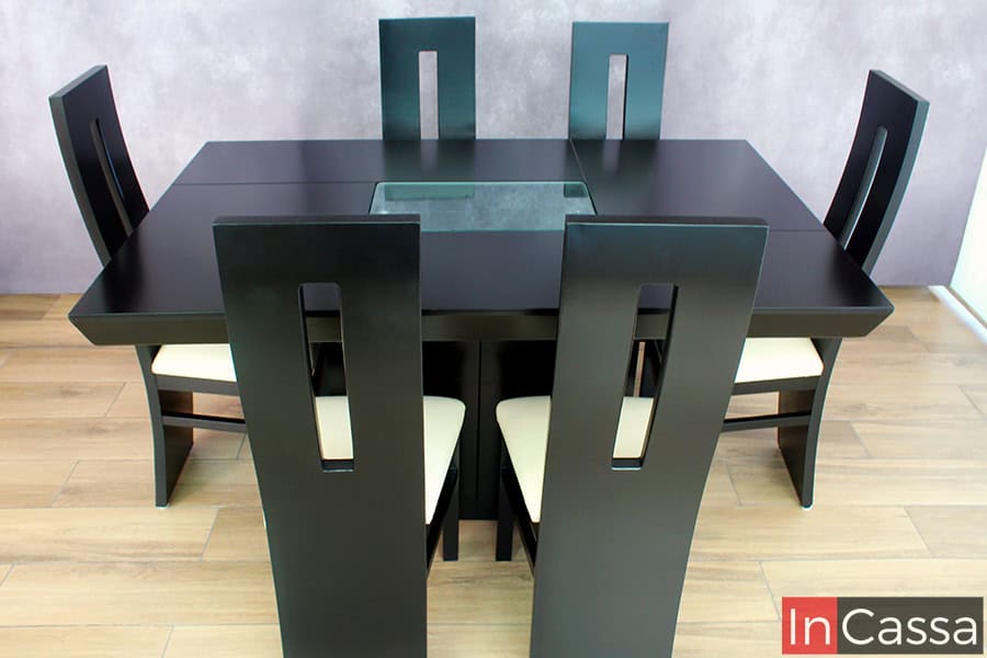 En esta imagen se aprecia una vista completamente frontal del comedor. Se destaca el diseño estilizado de las seis sillas con cortes geométricos en el respaldo, así como la mesa con cubierta chocolate y arenero central decorativo. Ideal para espacios contemporáneos.