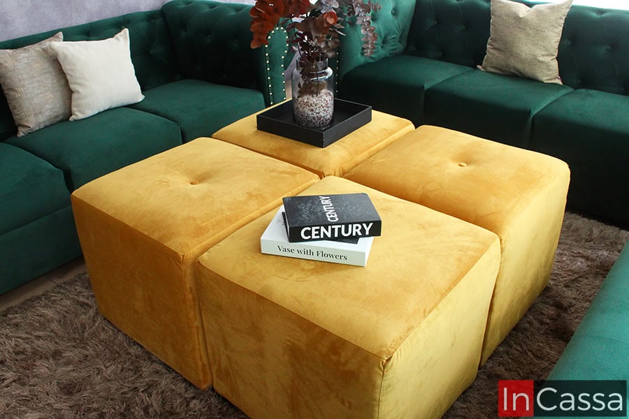 La imagen muestra el conjunto de cuatro taburetes del modelo San Petersburgo en tapizado suede dorado. Destacan su diseño minimalista y superficie acolchada, perfectos para complementar los sofás y el diván en verde botella.