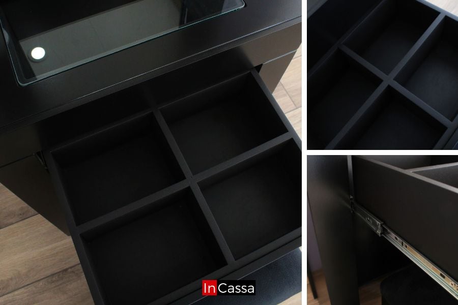 Una toma cercana resalta el cajón con divisiones internas del tocador Santorini en acabado negro. Se aprecian sus correderas metálicas y la cubierta de cristal, perfectas para mantener maquillaje y accesorios ordenados.