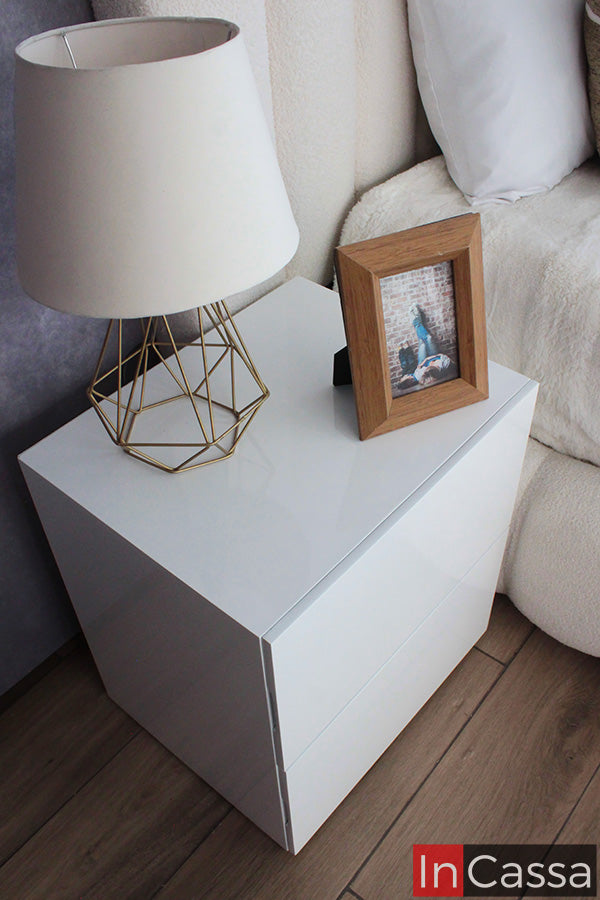 La fotografía muestra uno de los burós de la Recámara Viral Estilo Pinterest modelo SEDONA en acabado blanco brillante. Su diseño limpio y contemporáneo complementa perfectamente el tapizado suede hueso, creando una atmósfera elegante y luminosa.