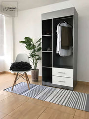 La imagen presenta una toma frontal completa del Guardarropa SHANGHAI, elaborado en color plata con cajones blancos y tiradores metálicos. Su diseño incluye espacio para colgar prendas y repisas abiertas que aportan orden y elegancia en un entorno moderno y luminoso.