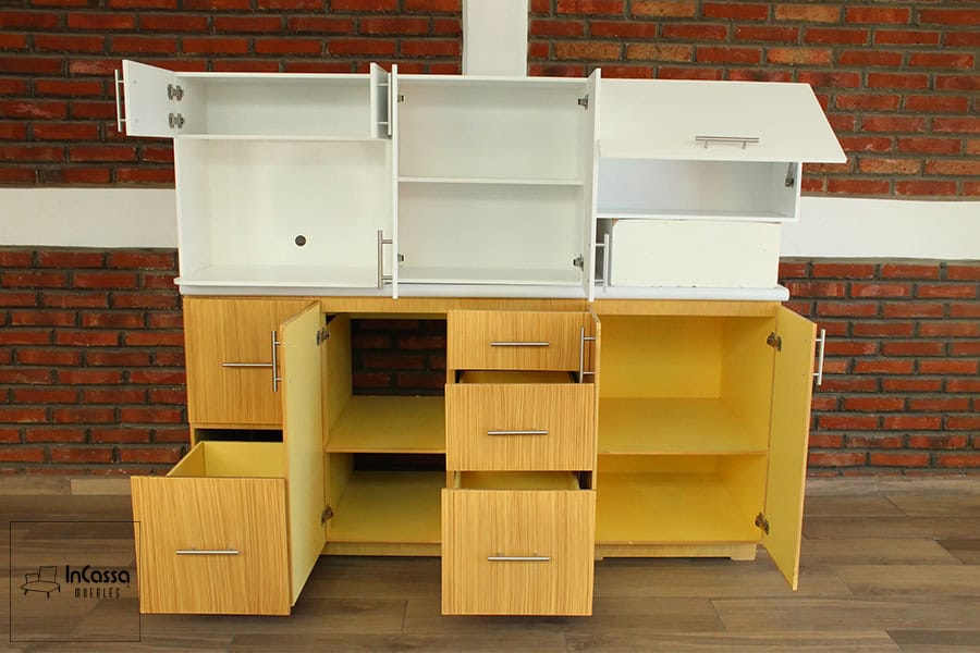 Una presentación de la cocina con todas sus puertas y cajones abiertos, mostrando todos los compartimentos disponibles. Tanto los interiores de los módulos superiores como del módulo inferior conservan el mismo tono que los exteriores de cada mueble, siendo los superiores de color blanco completo y el inferior de tono natural en su totalidad.